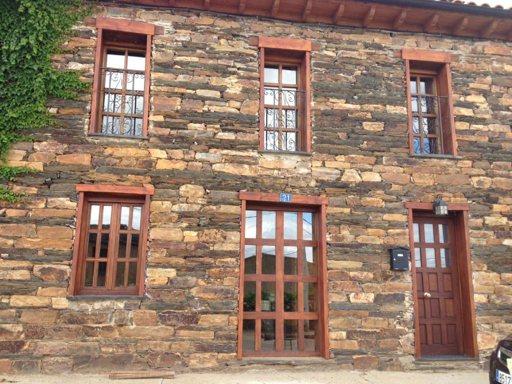 un edificio de piedra con seis ventanas. en Casa de piedra en Muga de Alba, en Muga de Alba