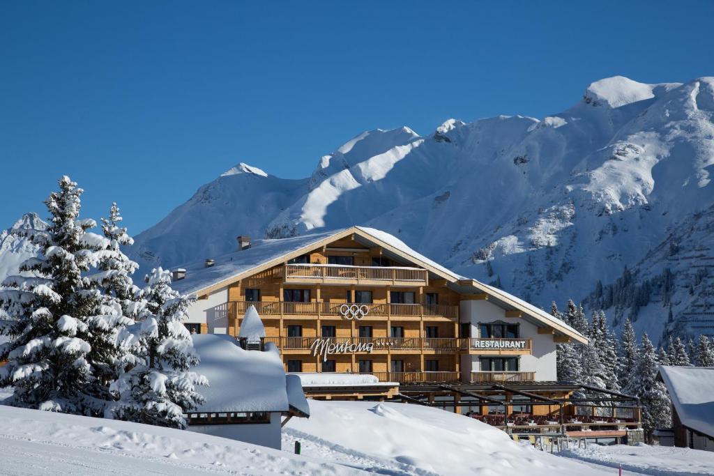 a ski lodge with snow covered mountains in the background at Hotel & Chalet Montana in Lech am Arlberg