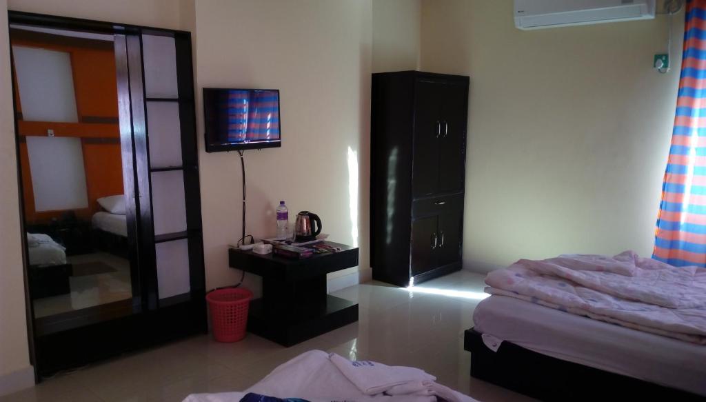 - une chambre avec un lit, un miroir et une télévision dans l'établissement Hotel Bay Wonders, à Cox's Bazar