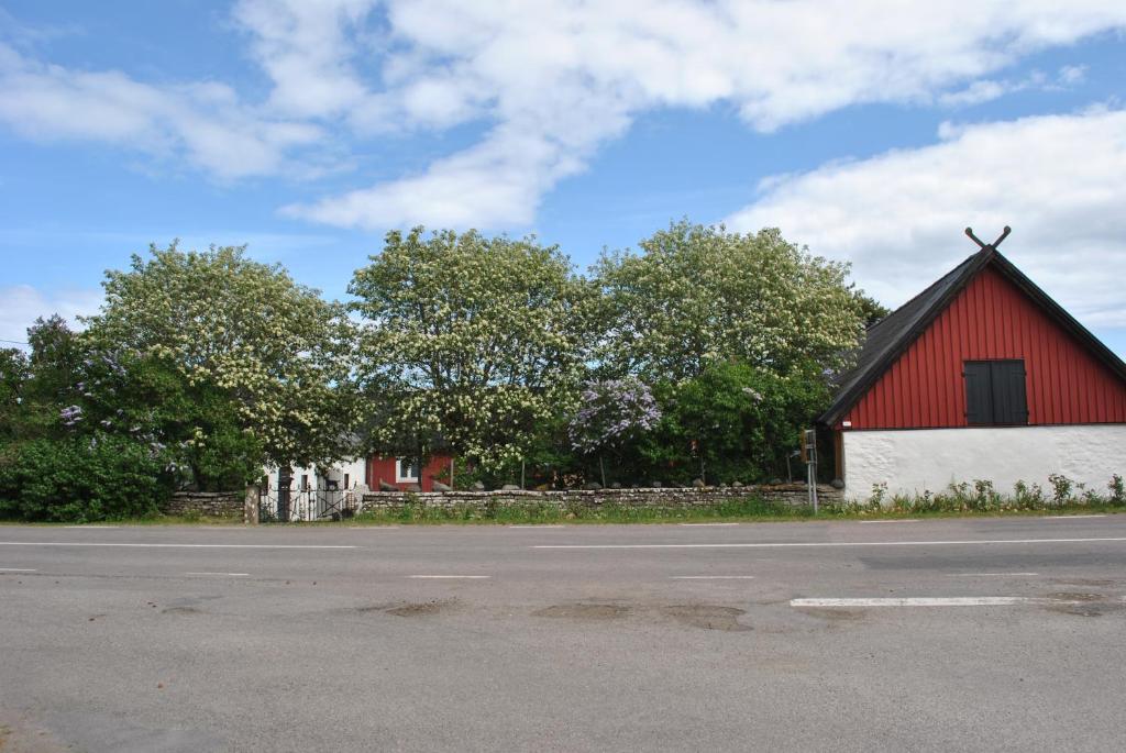 un granero rojo y blanco al lado de una carretera en Sandgårdsborg en Färjestaden