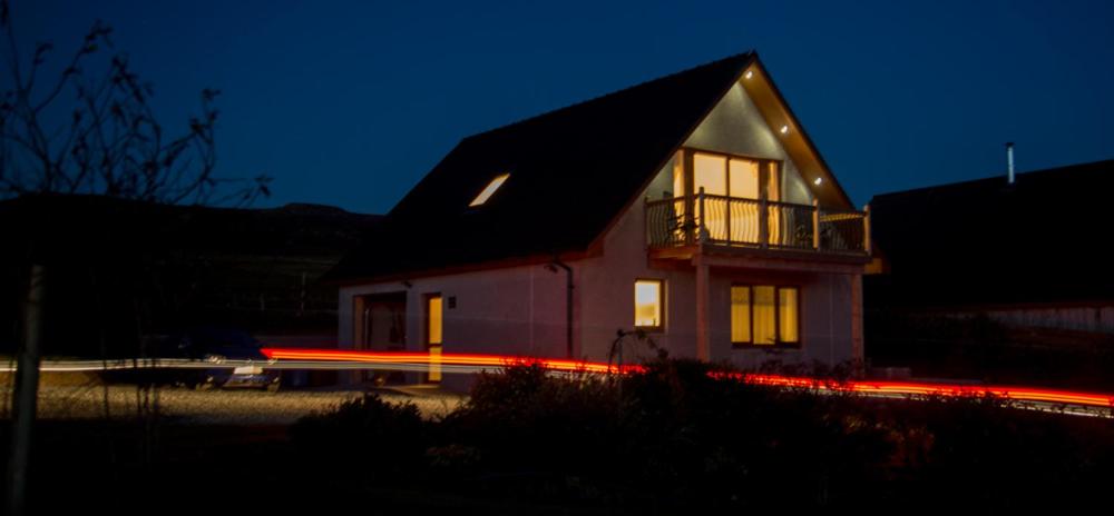 a house with a building with a balcony at night at Lochview Chalet in Eyre