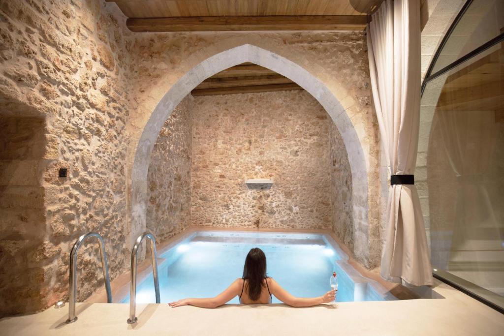 una mujer sentada en una bañera en una habitación en Monastery Estate Venetian Harbor en La Canea