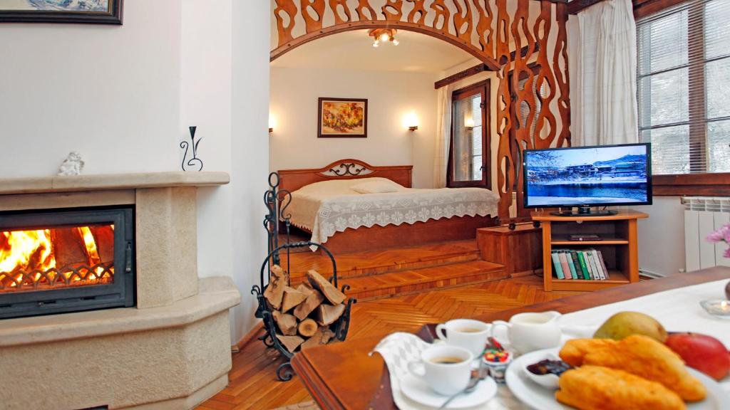 a living room with a fireplace and a bedroom with a bed at Family Hotel Varosha 2003 in Lovech