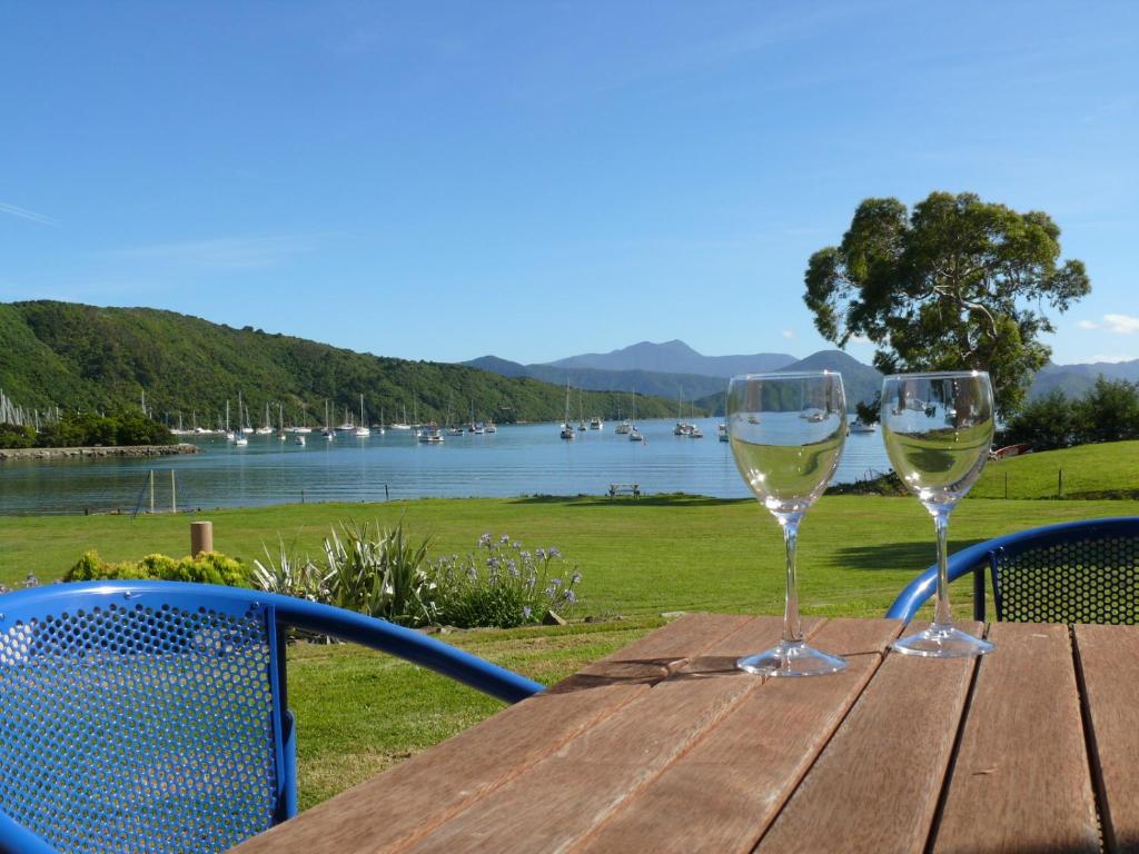 twee glazen witte wijn zittend op een houten tafel bij Bay Vista Waterfront Motel in Picton