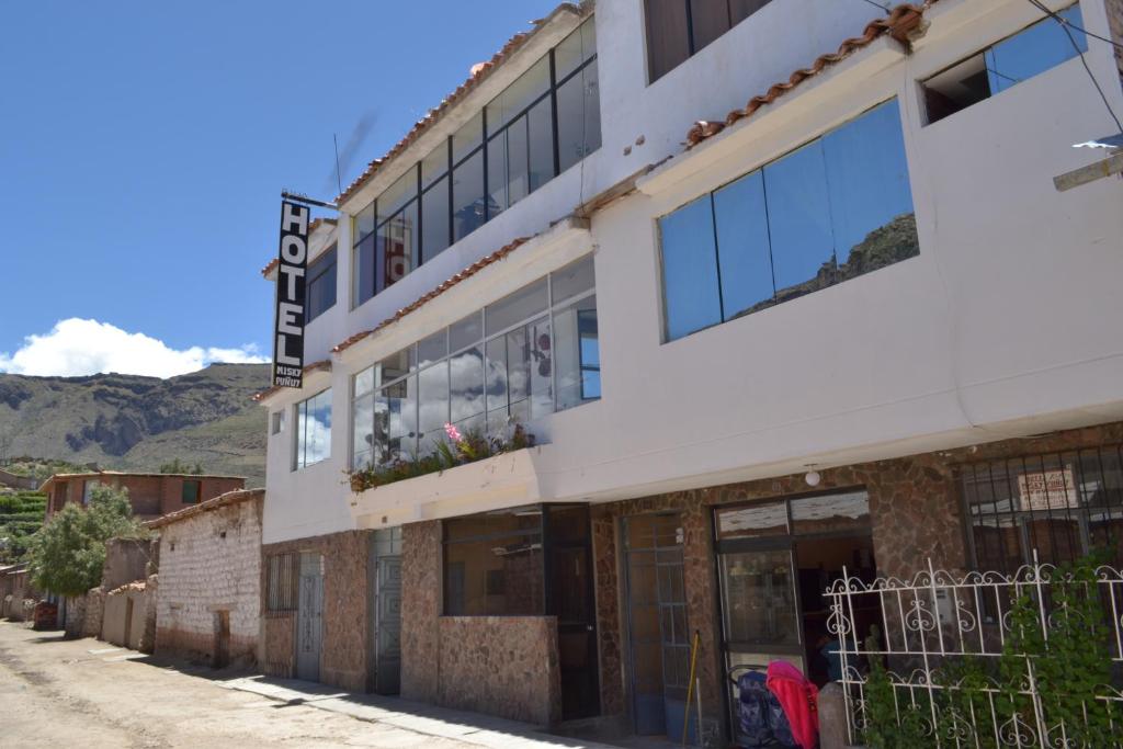 un edificio en una calle con montañas en el fondo en hotel MISKY PUÑUY - Valle del Sondondo, en Andamarca