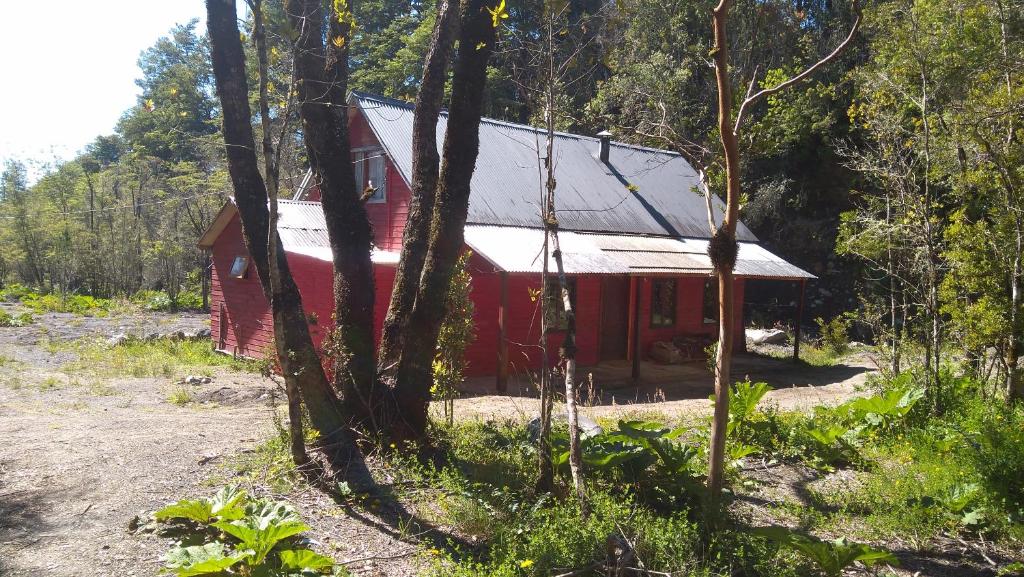 una cabaña roja en medio de un bosque en Casa del Rio, en La Ensenada