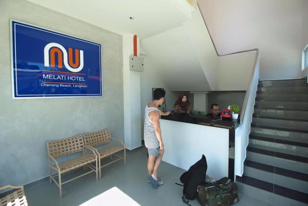 a man standing at a bar in a waiting room at Nu Melati Hotel in Pantai Cenang