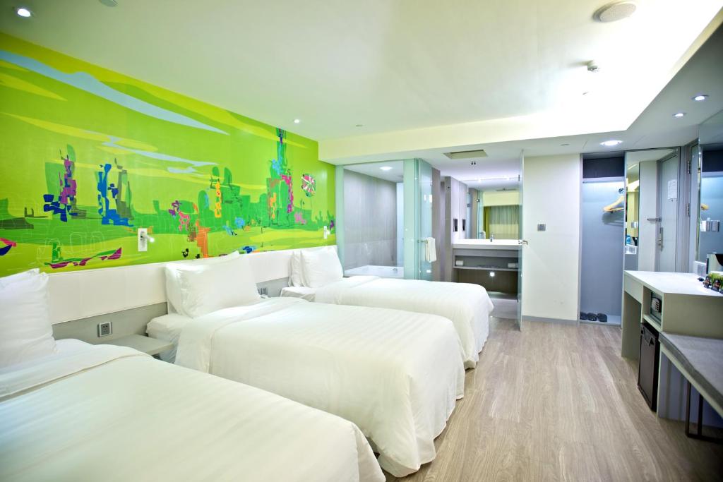 a hotel room with three beds and a bathroom at FX INN Kaohsiung Zhonghua Road Branch in Kaohsiung