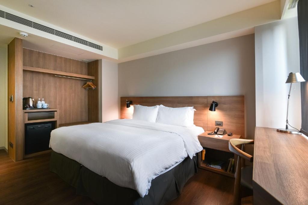 a hotel room with a large bed and a desk at Just Sleep Kaohsiung Zhongzheng in Kaohsiung