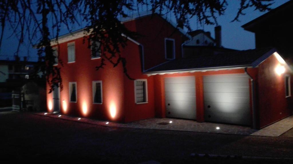 une maison rouge avec deux portes de garage la nuit dans l'établissement Residenza Il Salice, à Bagnolo San Vito