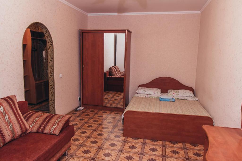 オムスクにあるApartment "Berloga 55" na Ordzhonikidzeのベッドルーム(ベッド1台、ソファ、鏡付)