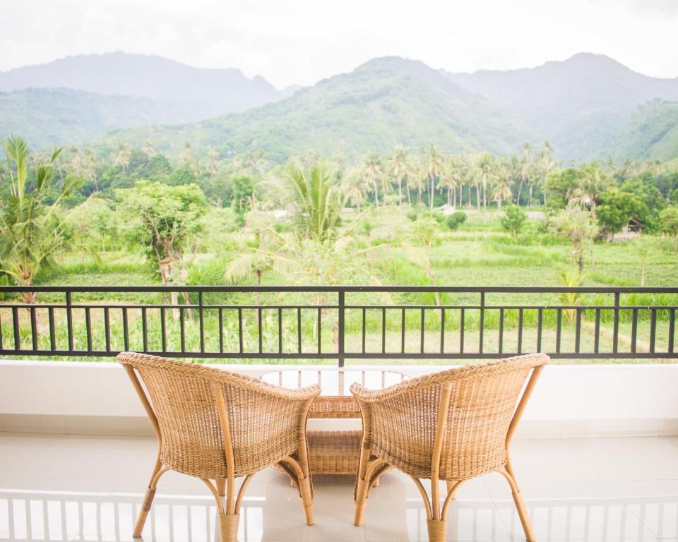 two chairs on a balcony with mountains in the background at d'Sawah Amed Homestay & Warung in Amed