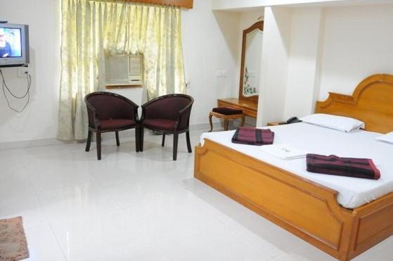 a bedroom with two beds and a table and chairs at Lloyds Guest House, North Boag Road, T. Nagar in Chennai