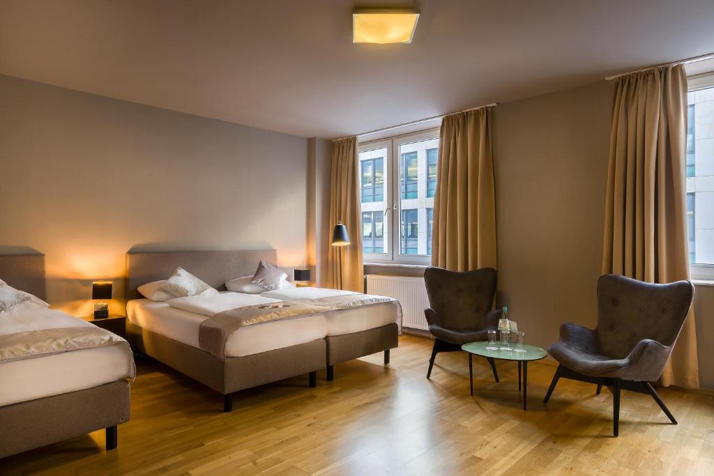 una camera d'albergo con due letti e un tavolo con sedie di Munique Hotel Frankfurt City a Francoforte sul Meno