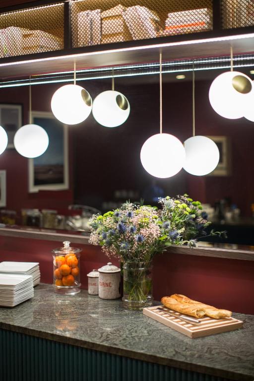 a counter in a restaurant with flowers and lights at ibis Styles Paris Nation Cours de Vincennes in Paris