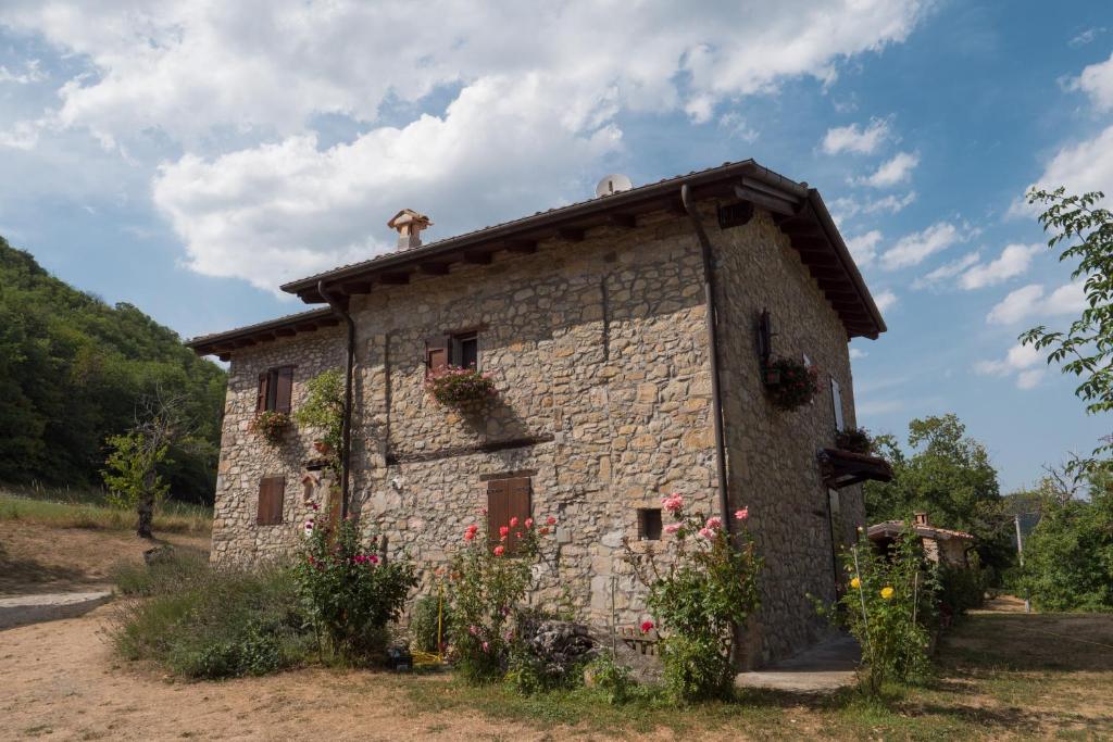 a small stone building with flowers in front of it at La Piana Dei Castagni in Castel dʼAiano