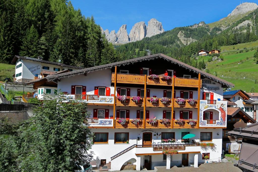 a hotel with balconies and flowers on a mountain at Hotel Fiorenza in Campitello di Fassa