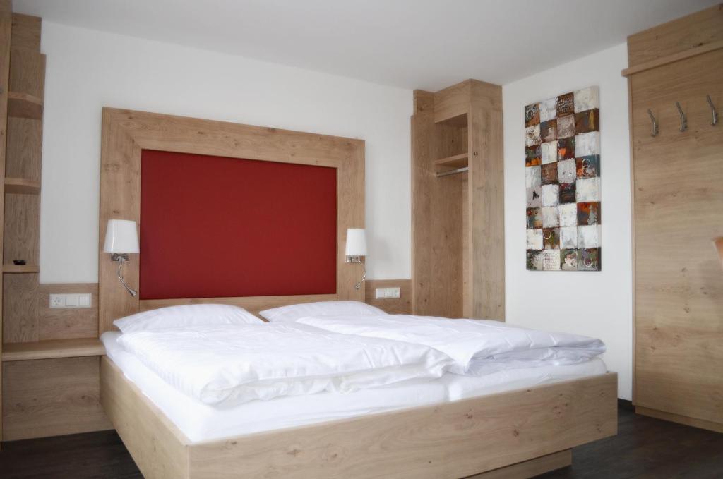 - une chambre avec un grand lit blanc et une tête de lit rouge dans l'établissement Landhotel Schwarzer Adler, à Tiefenbronn
