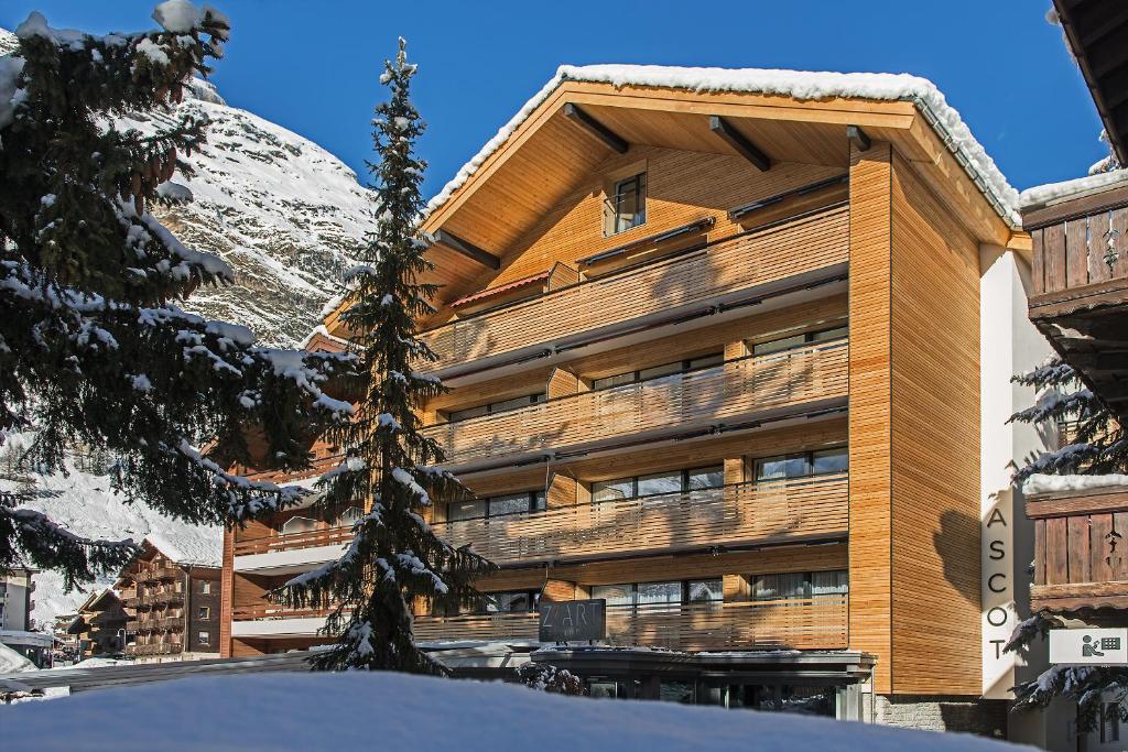 een groot gebouw met een met sneeuw bedekte berg bij Ascot-Zermatt in Zermatt