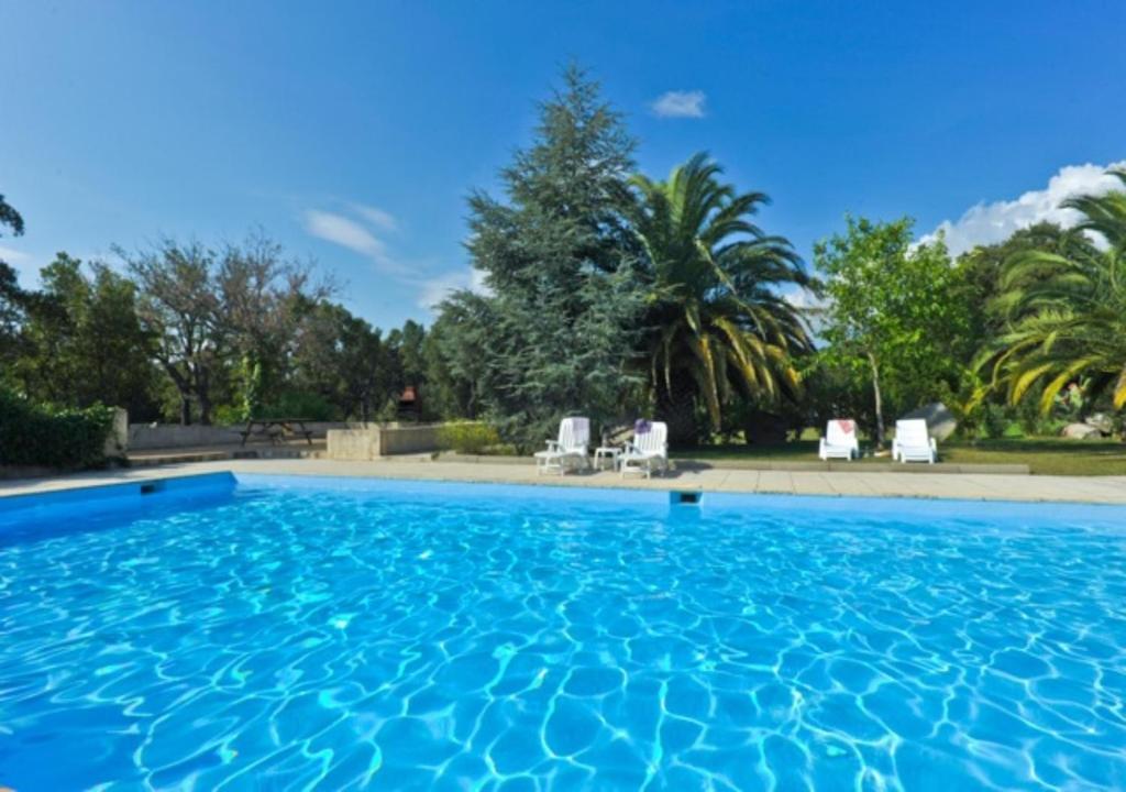 een groot zwembad met blauw water in een tuin bij Domaine Valdaronu in Sainte-Lucie de Porto-Vecchio