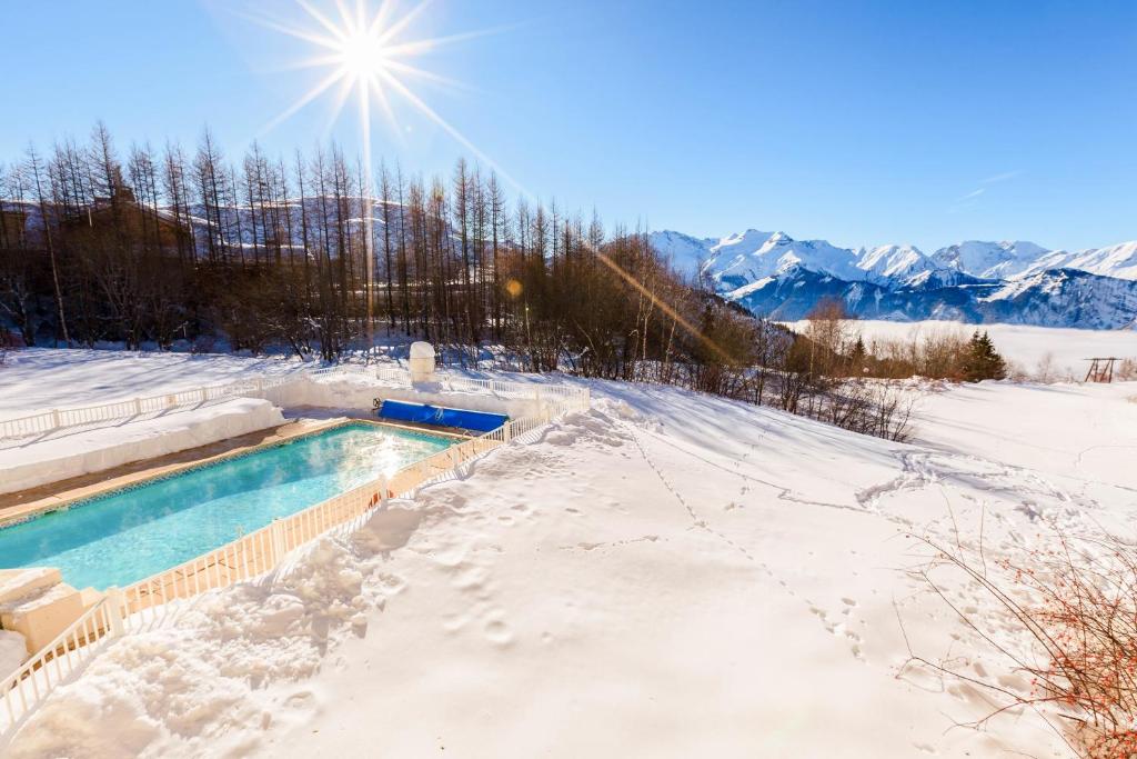 a swimming pool covered in snow with mountains in the background at Residence Les Bergers - maeva Home in L'Alpe-d'Huez