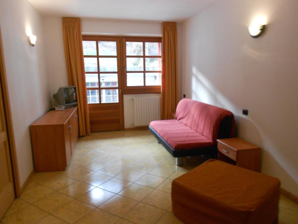 uma sala de estar com uma cadeira vermelha e uma televisão em Residence Le Orchidee em Bormio