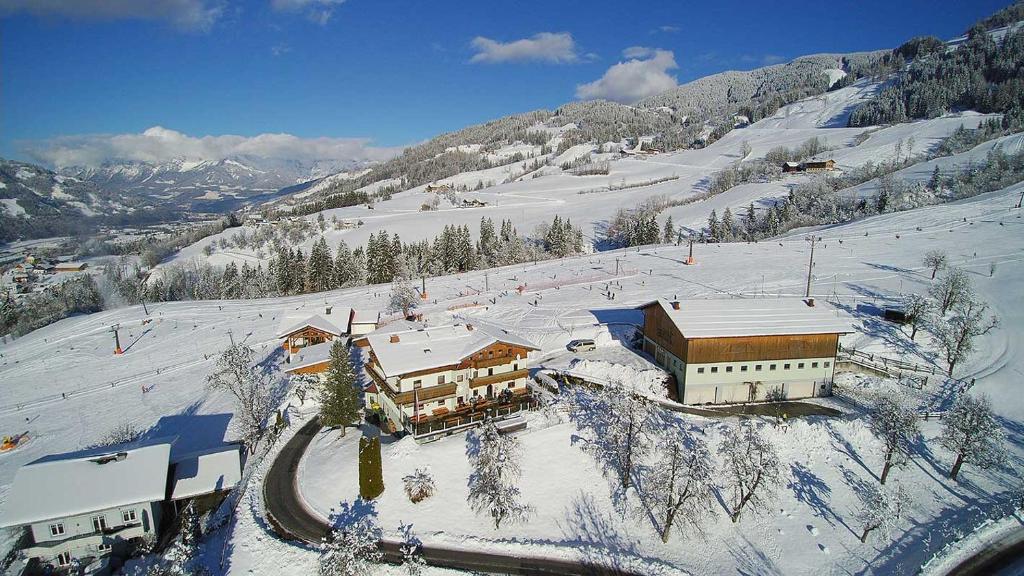 a building on a snow covered slope with a mountain at Gasthof Pension Hetzenbichl in Sankt Johann im Pongau