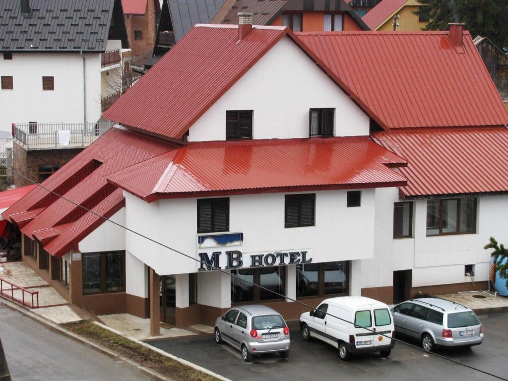 ein Hotel mit Autos auf einem Parkplatz in der Unterkunft MB Hotel in Žabljak