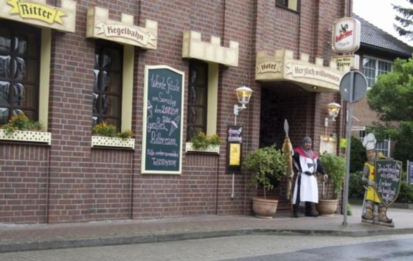 une personne en costume debout à l'extérieur d'un bâtiment en briques dans l'établissement Hotel Restaurant Zum Alten Ritter, à Bad Bodenteich