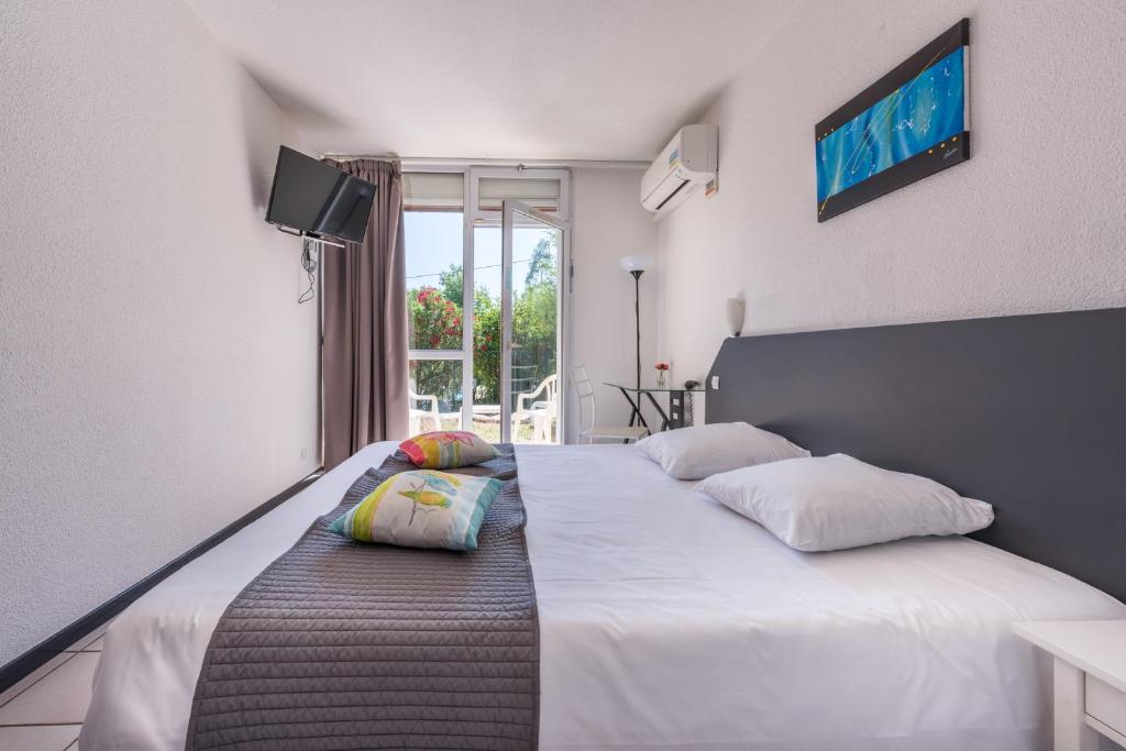 a bedroom with two beds and a tv on the wall at Le Clos des Bruyères in Vallon-Pont-dʼArc