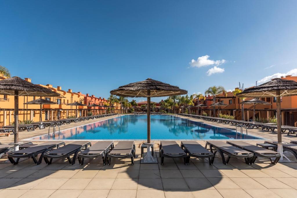 uma piscina com cadeiras e guarda-sóis em frente a um resort em Luxury Apartment, Marina, Beach & Pool em Portimão