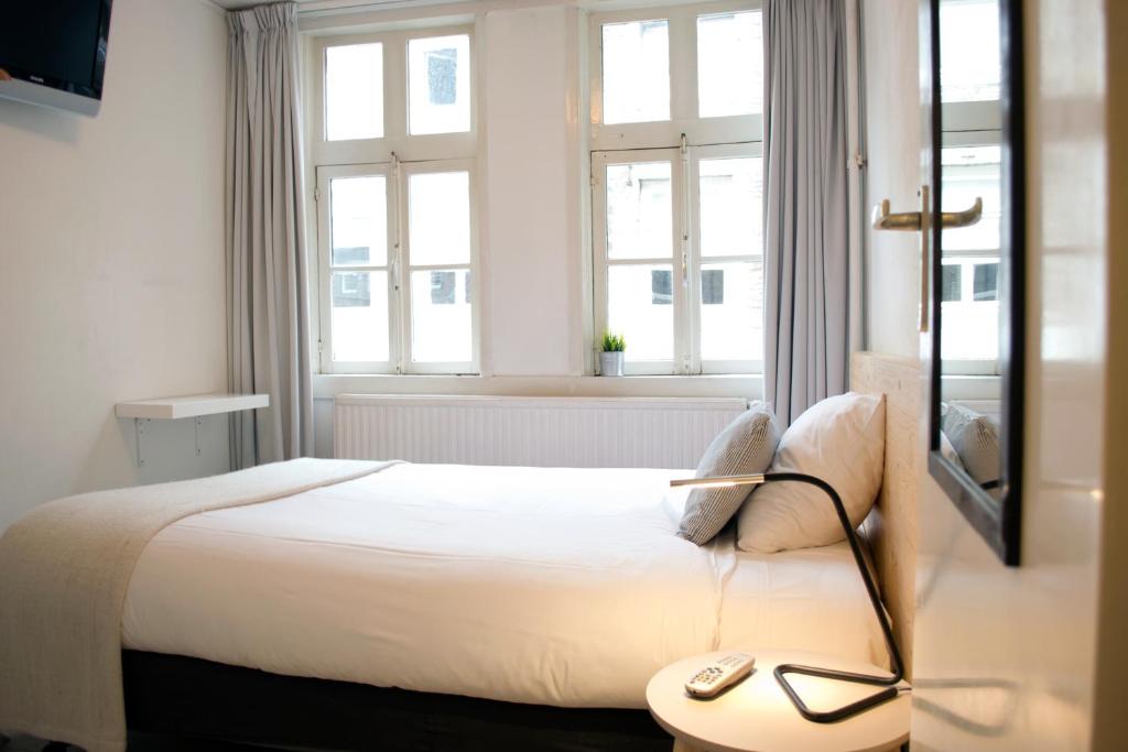 a bedroom with a bed with a table and windows at Hotel Beez in Maastricht