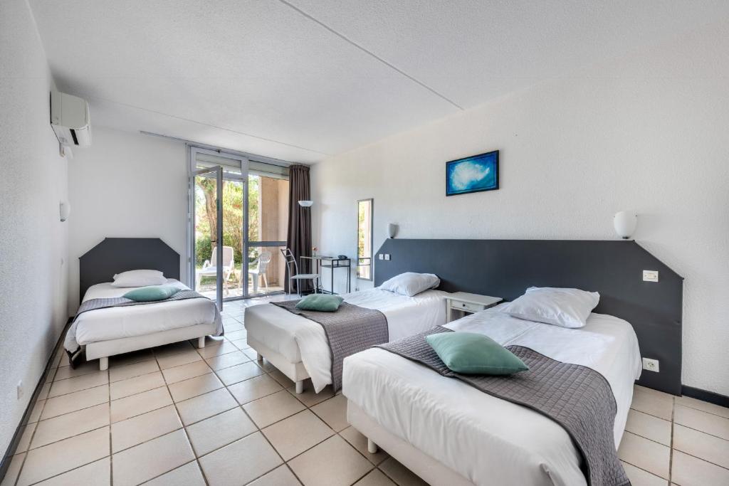a hotel room with two beds and a balcony at Le Clos des Bruyères in Vallon-Pont-dʼArc