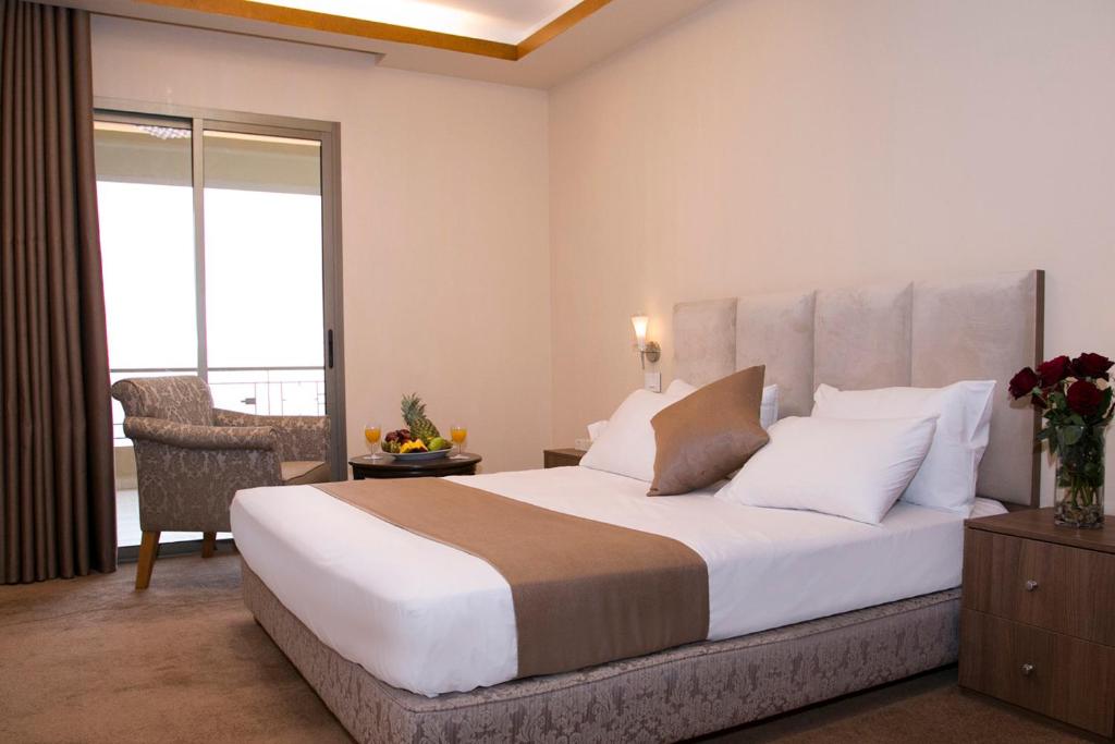 a bedroom with a large white bed and a chair at Bzommar Palace Hotel in Harisa