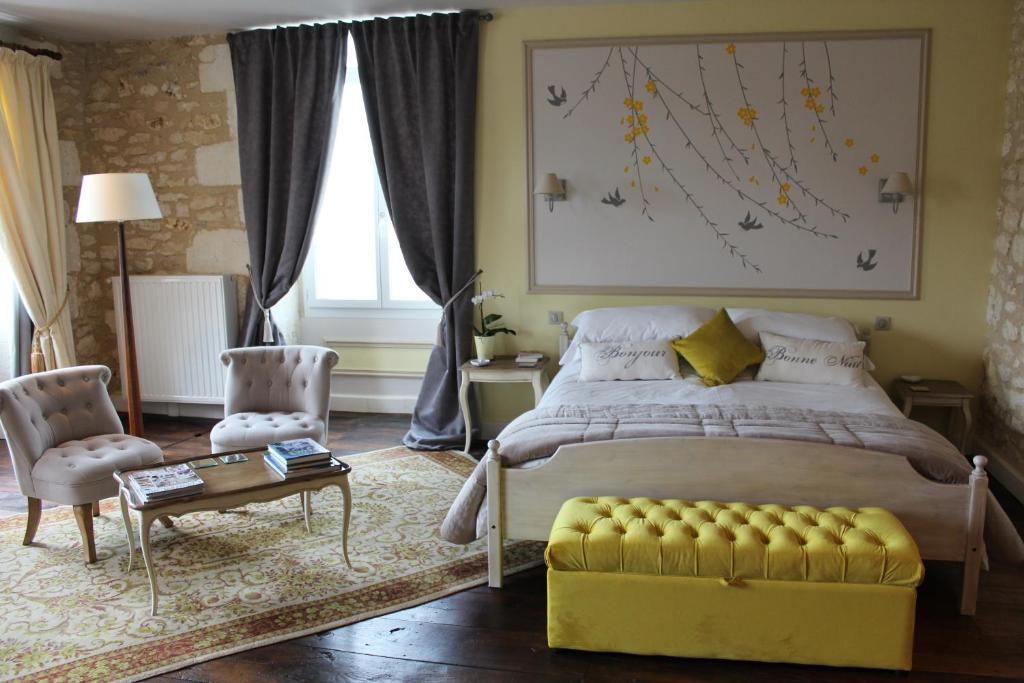 sypialnia z dużym łóżkiem i żółtą kanapą w obiekcie Le Patio Chambres et Tables d'Hôtes w mieście La Tour-Blanche