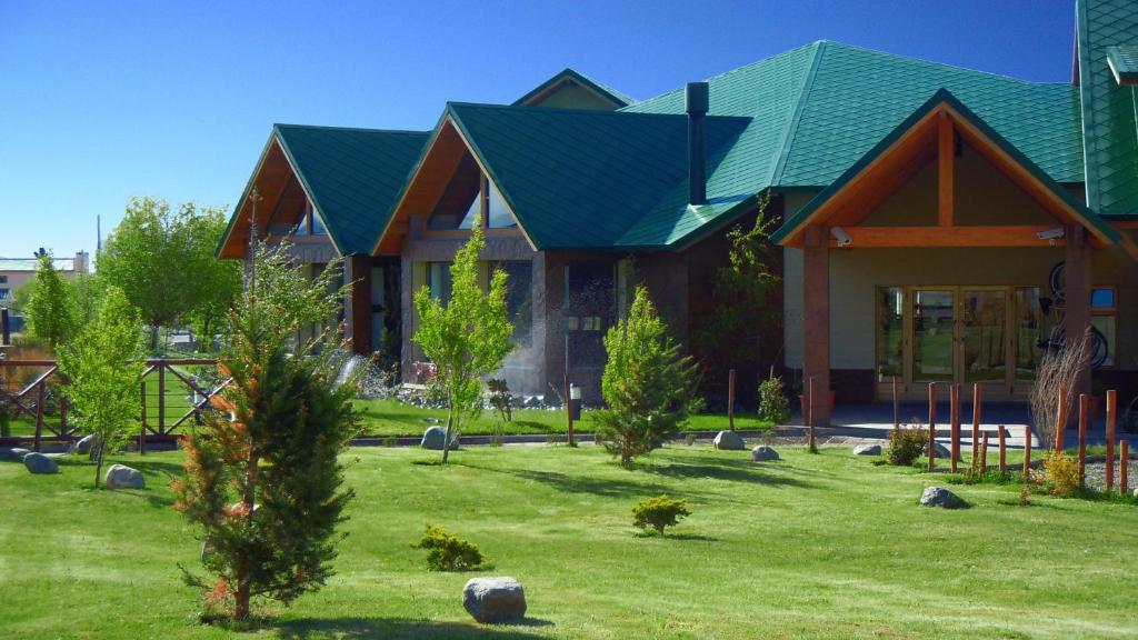 a house with a green roof on a lawn at Konke Calafate Hotel in El Calafate