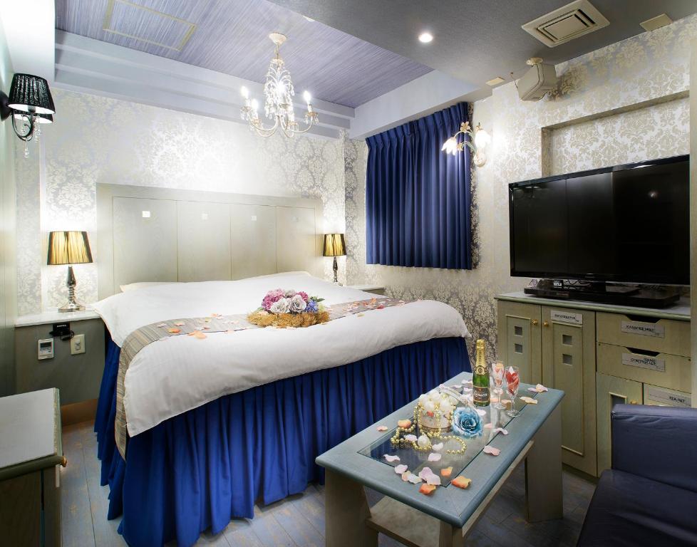 ein Schlafzimmer mit einem großen Bett und einem TV in der Unterkunft ホテル リトルチャペルクリスマス 梅田 in Osaka