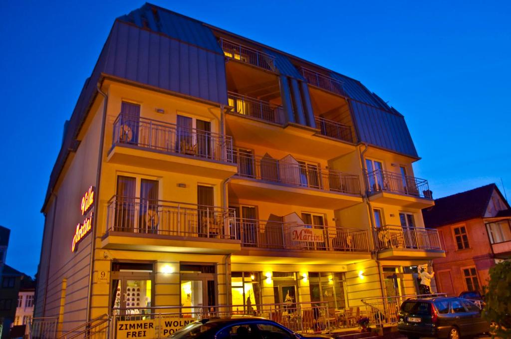 a yellow building with balconies and cars parked in front of it at Villa Martini in Międzyzdroje