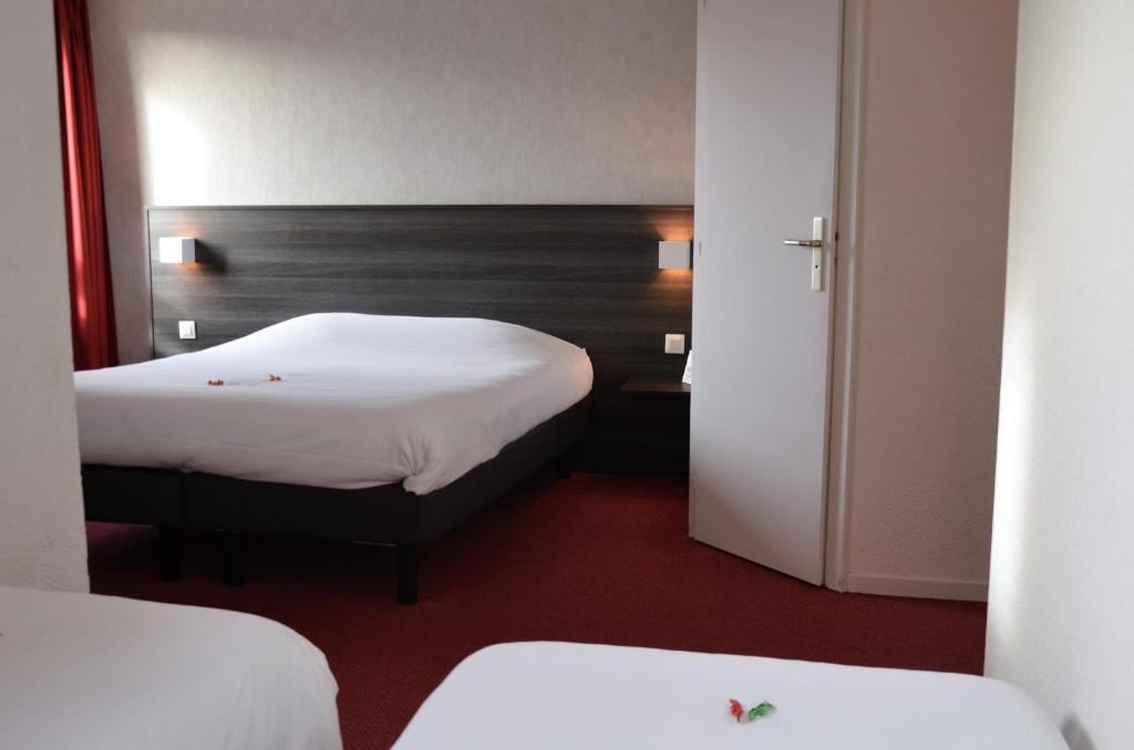 a hotel room with two beds and a mirror at The Originals City, Hôtel Amys, Tarbes Sud (Inter-Hotel) in Odos