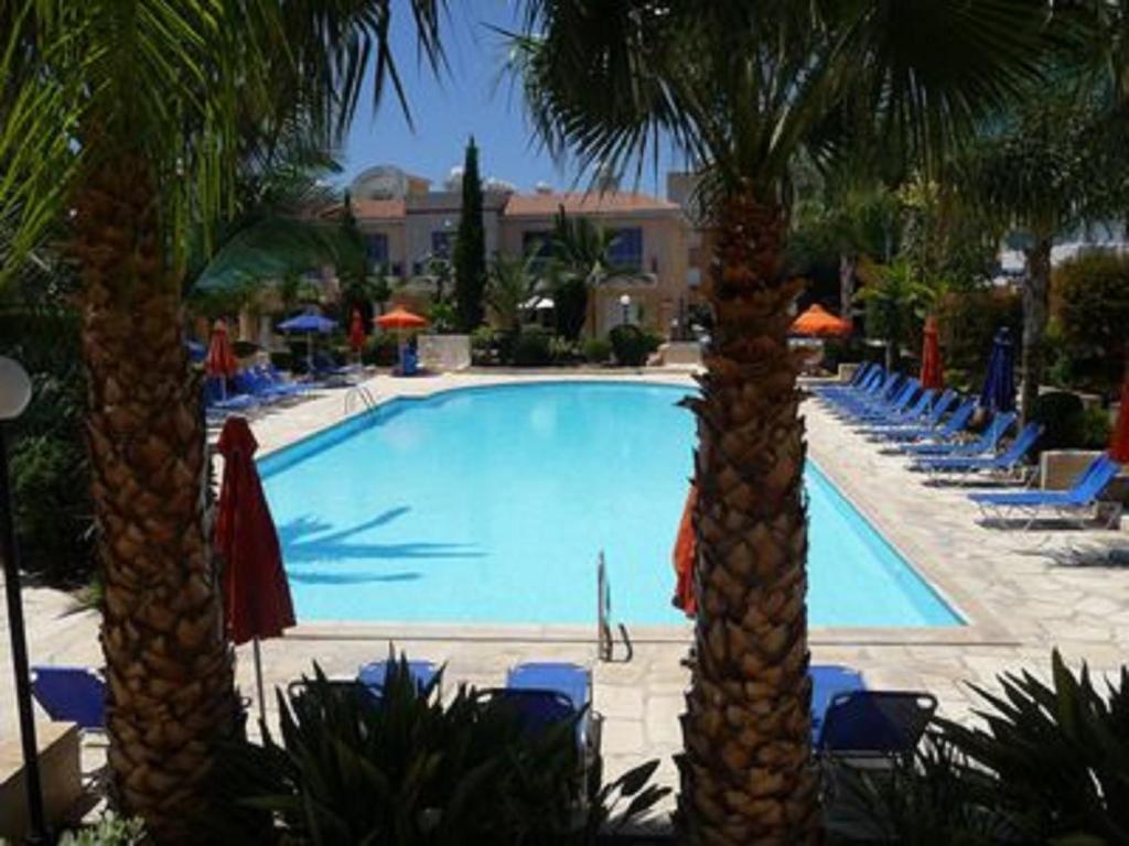 a swimming pool with two palm trees and chairs at Aurora Townhouse - Complimentary Paphos Airport Transport in Paphos City