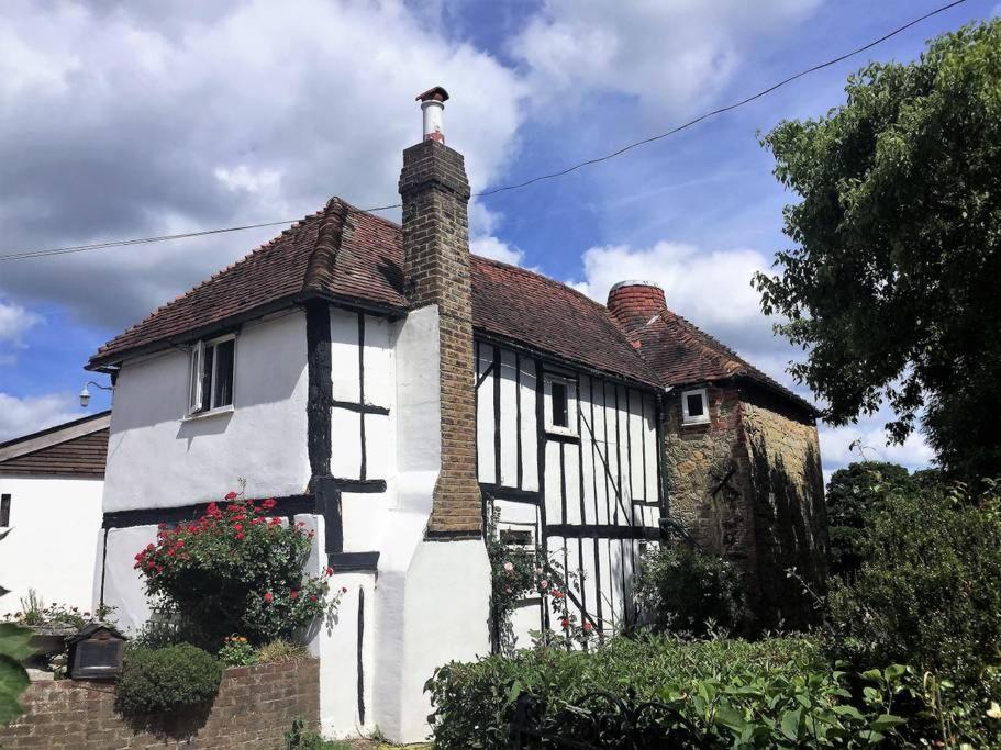 una casa bianca e nera con camino di Ockhams Farm Guest House a Edenbridge