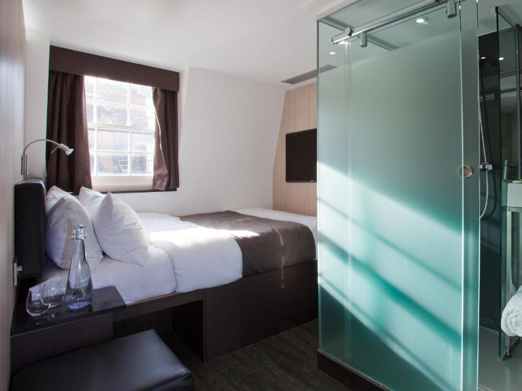 a hotel room with a bed and a glass shower at The Z Hotel Soho in London