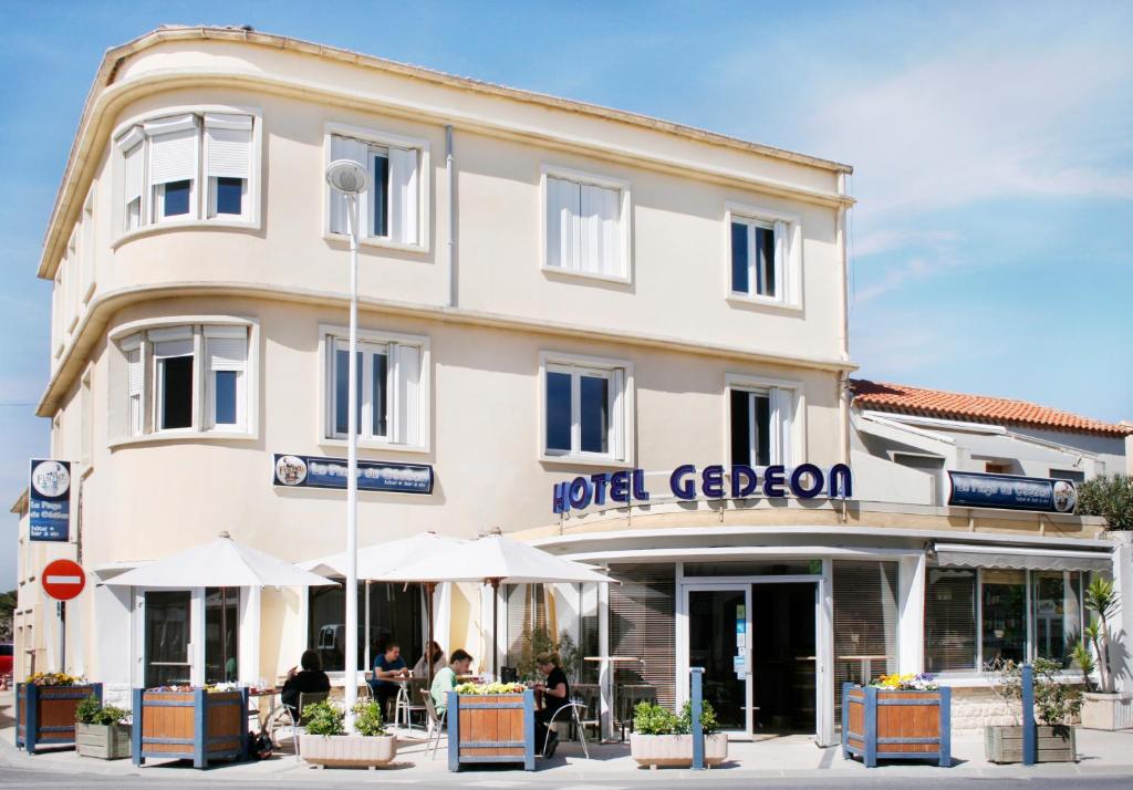 un edificio con gente sentada fuera de él en Hôtel Restaurant Gédéon, en Carnon-Plage