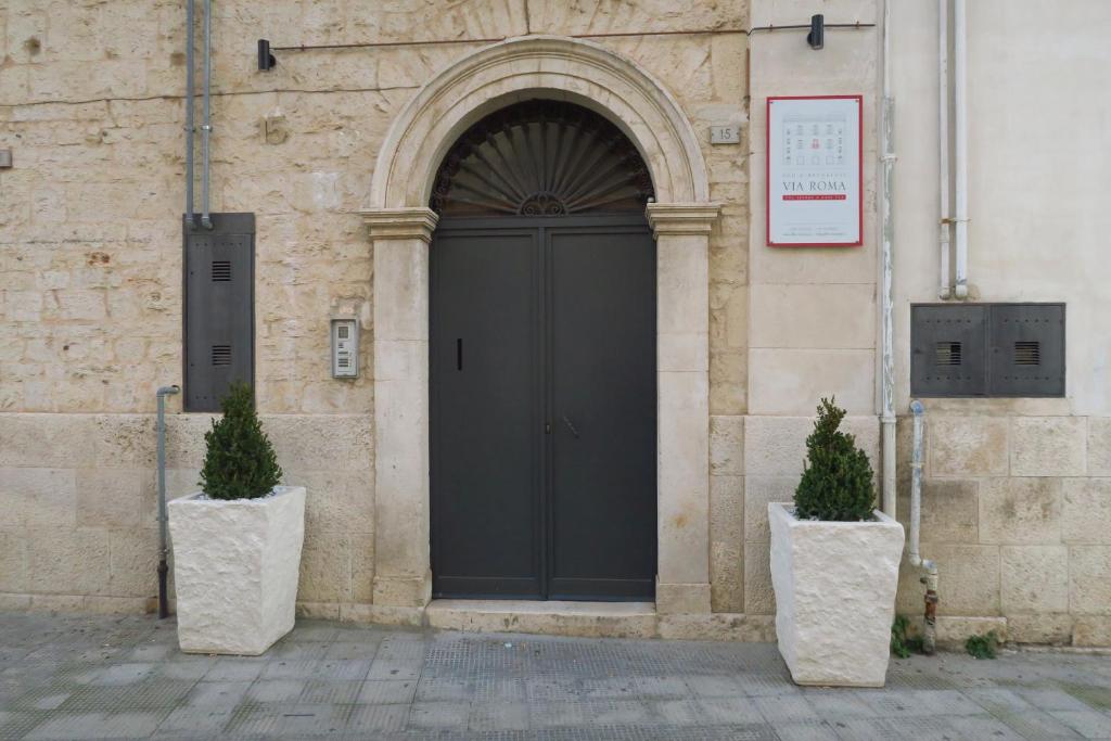 een deur van een gebouw met twee planten ervoor bij B&B Via Roma 15 in Acquaviva delle Fonti