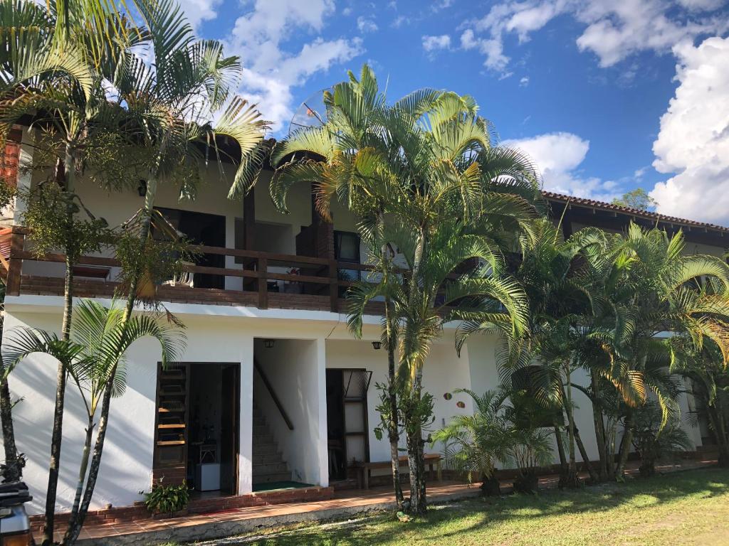 una casa con palmeras delante en Pousada Farol do Marinheiro en Boicucanga