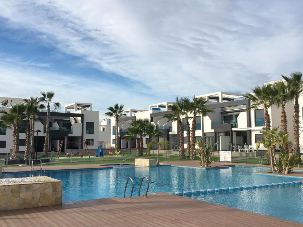 un complejo con piscina con palmeras y edificios en Casa de la vida La Zenia en Playas de Orihuela