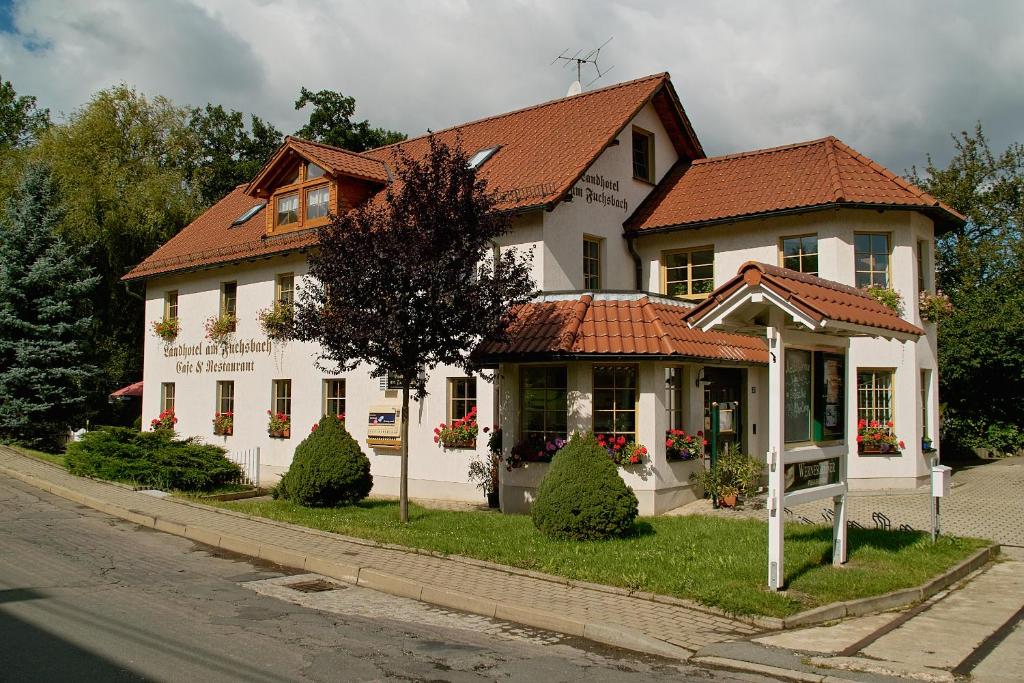 a white house with a red roof on a street at Landhotel am Fuchsbach in Berga