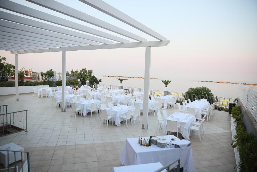 una marquesina con mesas blancas y sillas en un patio en Hotel Dolce Stella, en Torre Melissa