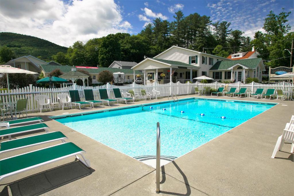 a swimming pool with chairs and a house at The Heritage of Lake George in Lake George