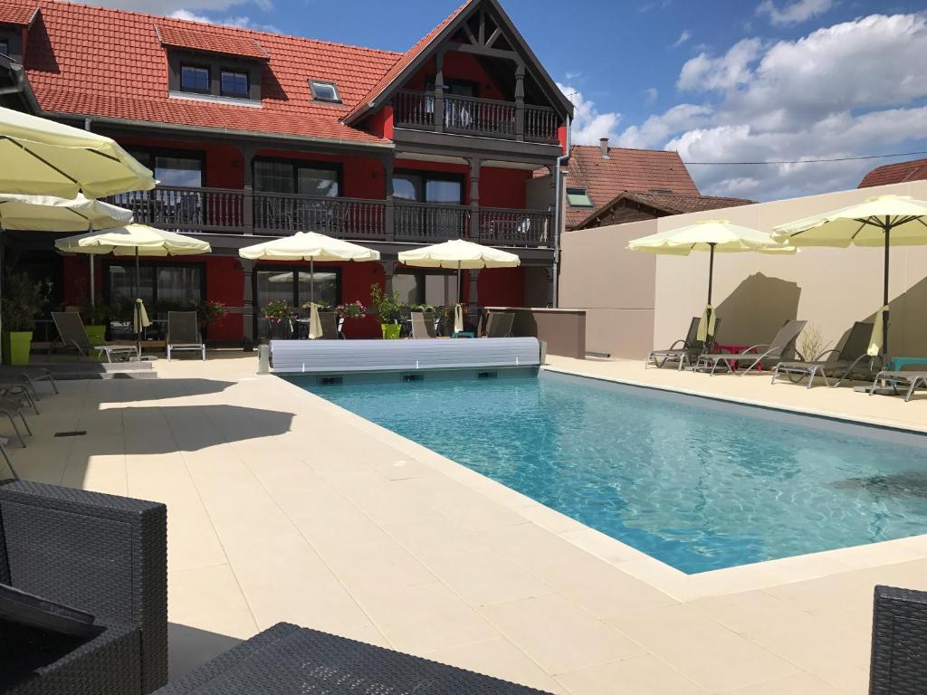 - une piscine avec des chaises et des parasols à côté d'un bâtiment dans l'établissement Au Soleil, Hôtel Restaurant & Spa, à Valff